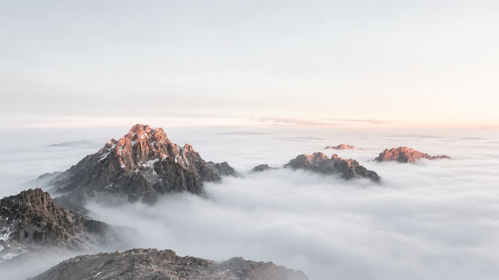 Mountain summits catching first light above an unbroken sea of cloud